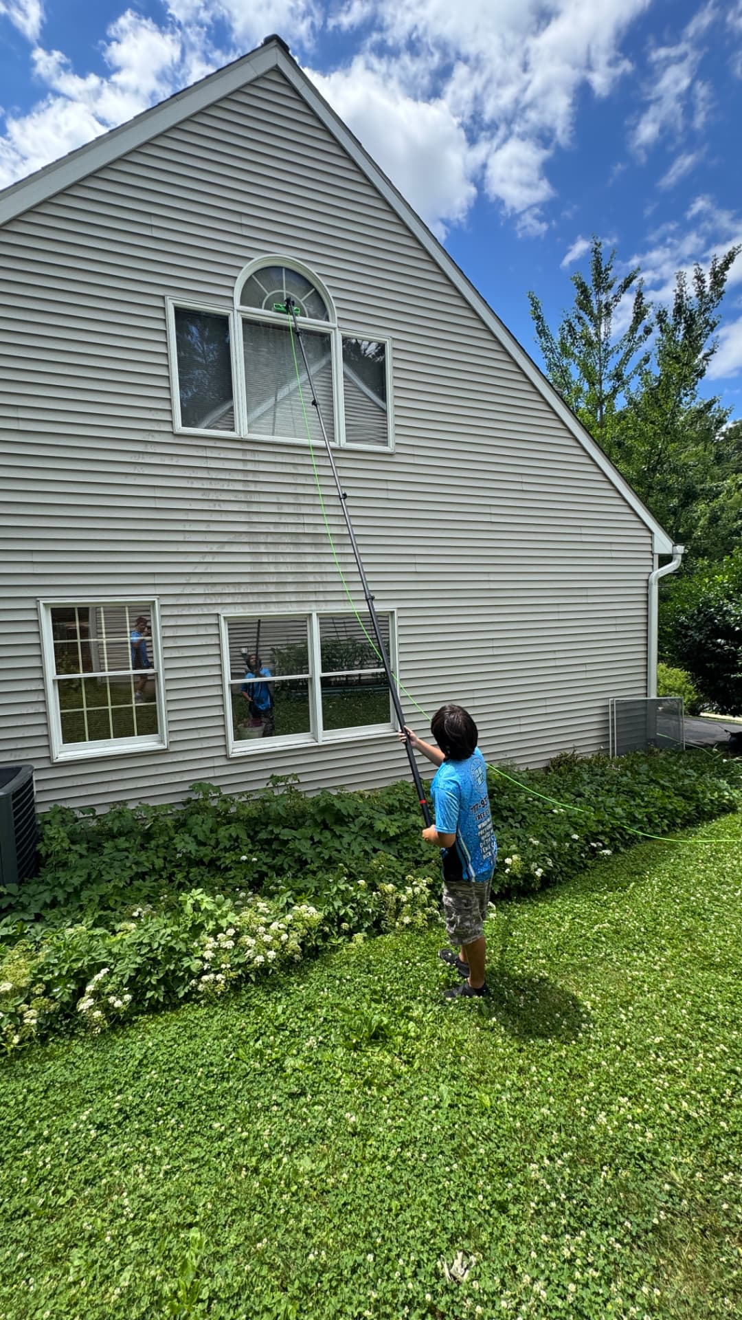 Beine & Beisker team member cleaning gable windows with a water-fed pole